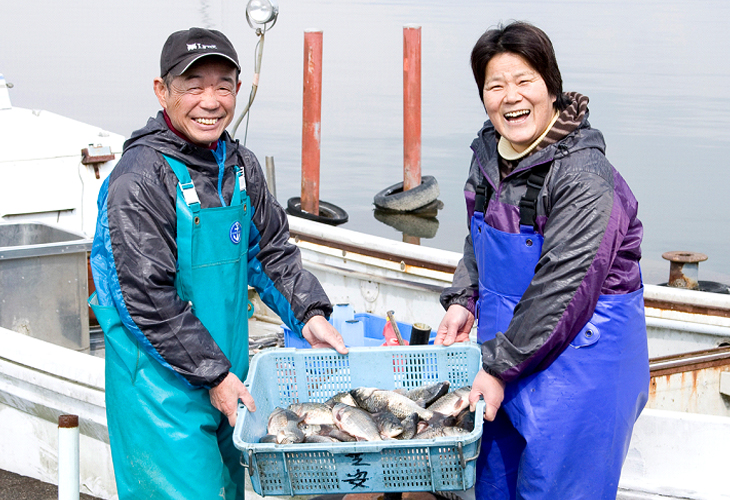 守山市の木浜漁港で、朝獲れたニゴロブナを手にする芝原さんご夫妻
